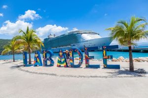 Woman leaning on large painted letters spelling out "Labadee" on the beach of Royal Caribbean's private coastal peninsula of Labadee, Haiti